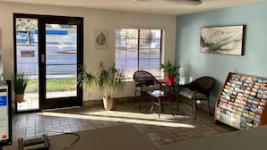A room with a tiled floor, a desk with a computer, a chair, a potted plant, a window with blinds, and a wall-mounted art piece. - Premier Inns Concord (Concord)