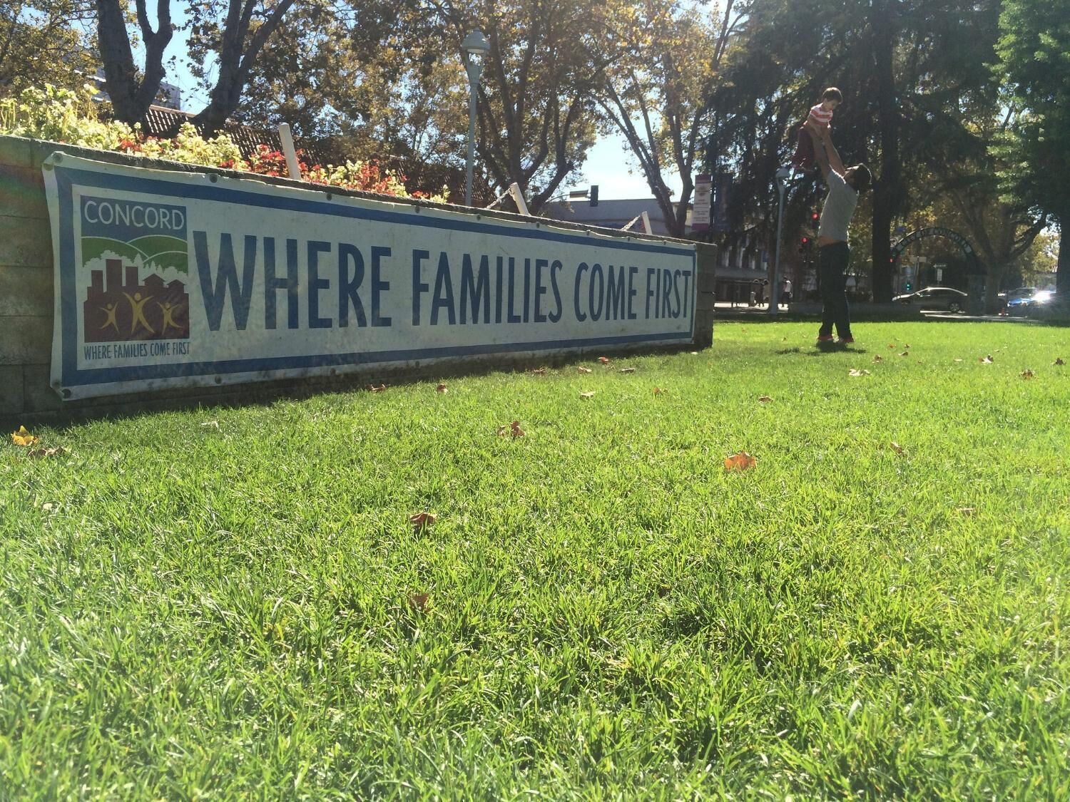 A sign with the text "WHERE FAMILIES COME FIRST" and a logo with a family and a building.