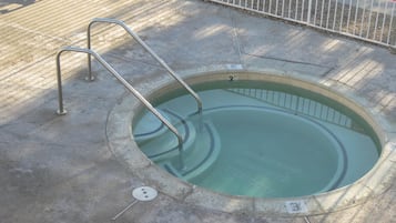Een klein, rond zwembad met een metalen trap en een afdeksel voor de afvoer.