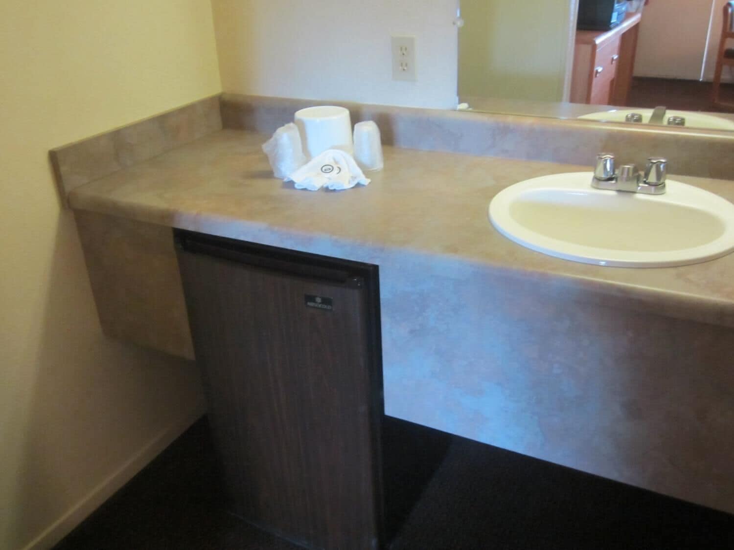 A bathroom with a sink, mirror, and a small cabinet.