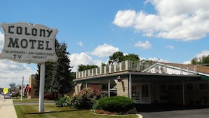 A Colony Motel sign with amenities like telephones, air conditioning, TV, and vacancy information.