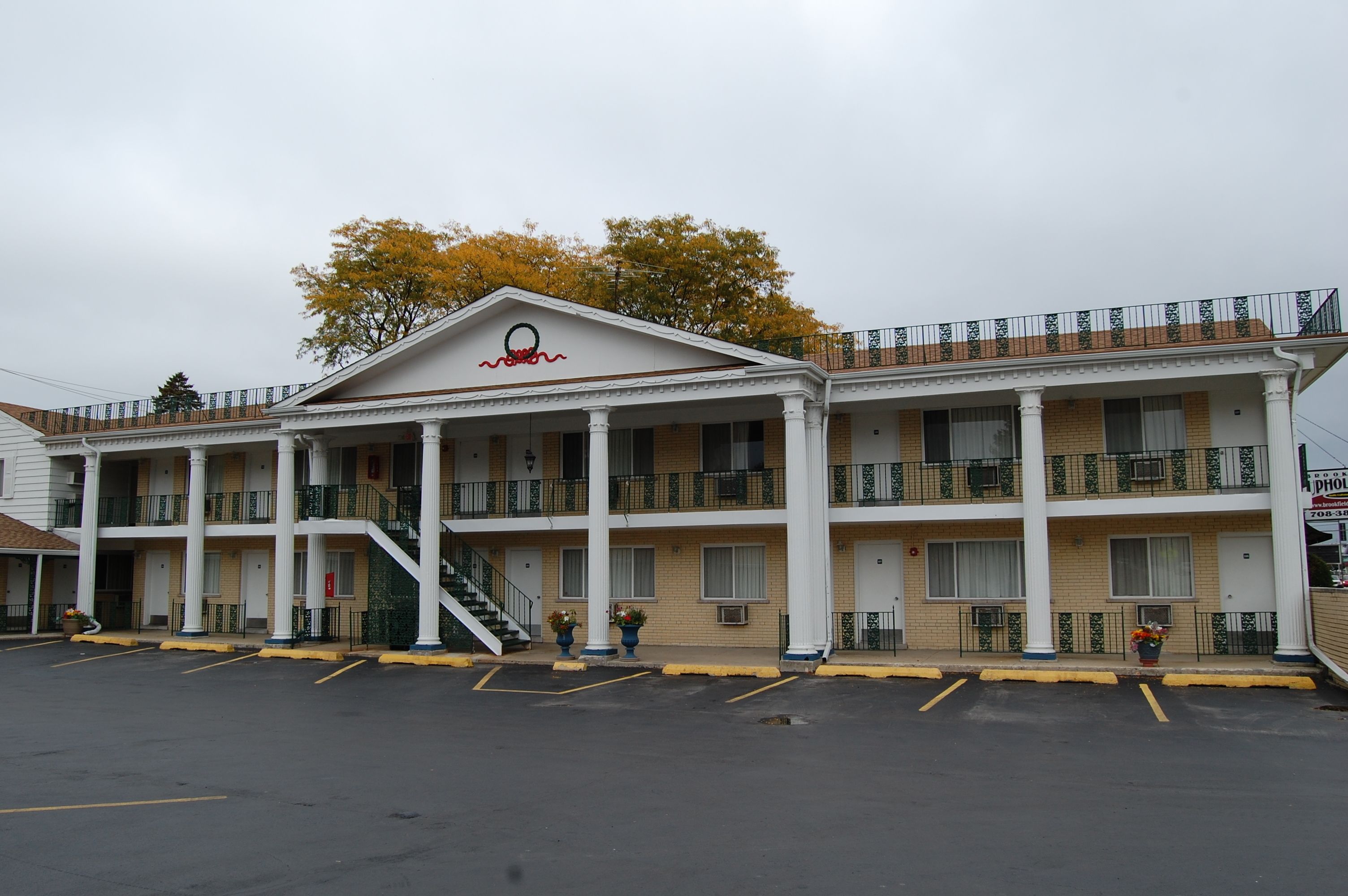 A two-story motel with a central entrance, a covered porch, and a parking lot.