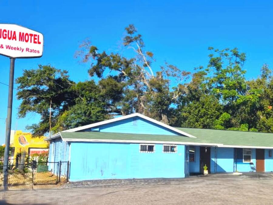 Ein Motel mit blauer Fassade und einem Schild, das Tages- und Wochenpreise anzeigt.