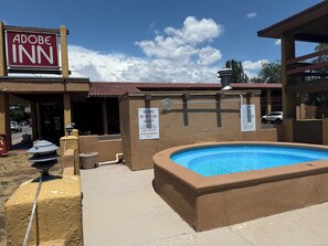 An Adobe Inn with a pool area, a sign warning about no lifeguard on duty, and a building with a red-tiled roof.