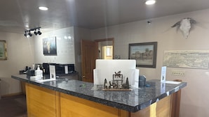 A kitchen with granite countertops, wooden cabinets, a coffee machine, and a decorative moose model. - Adobe Inn (Durango)