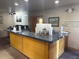 Una cocina con encimeras de granito, armarios de madera, una cafetera y un modelo decorativo de alce.