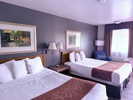 Habitación de hotel con dos camas, un escritorio, una silla y dos lámparas fijadas a la pared.