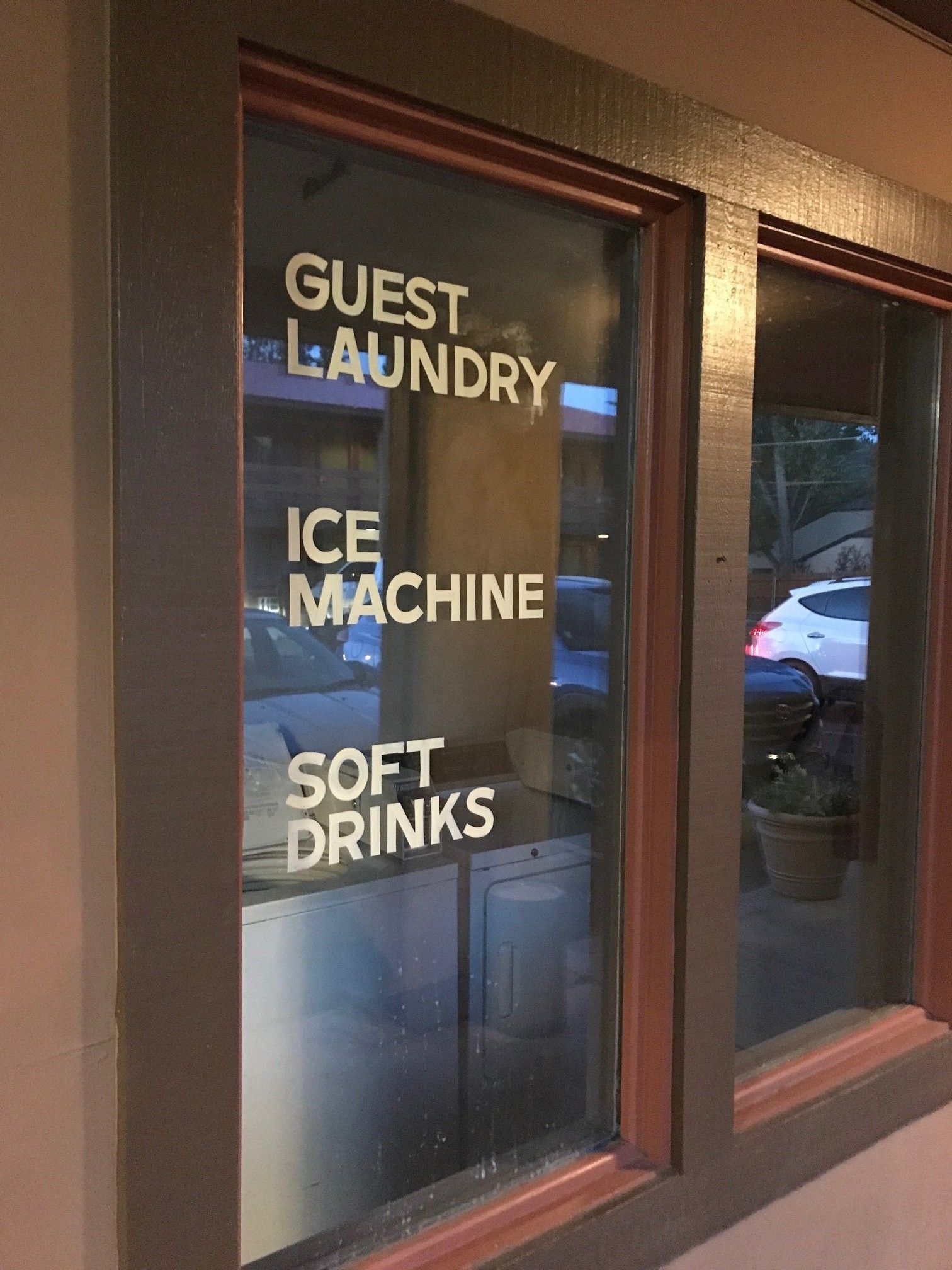 A window with a sign listing amenities: guest laundry, ice machine, and soft drinks.
