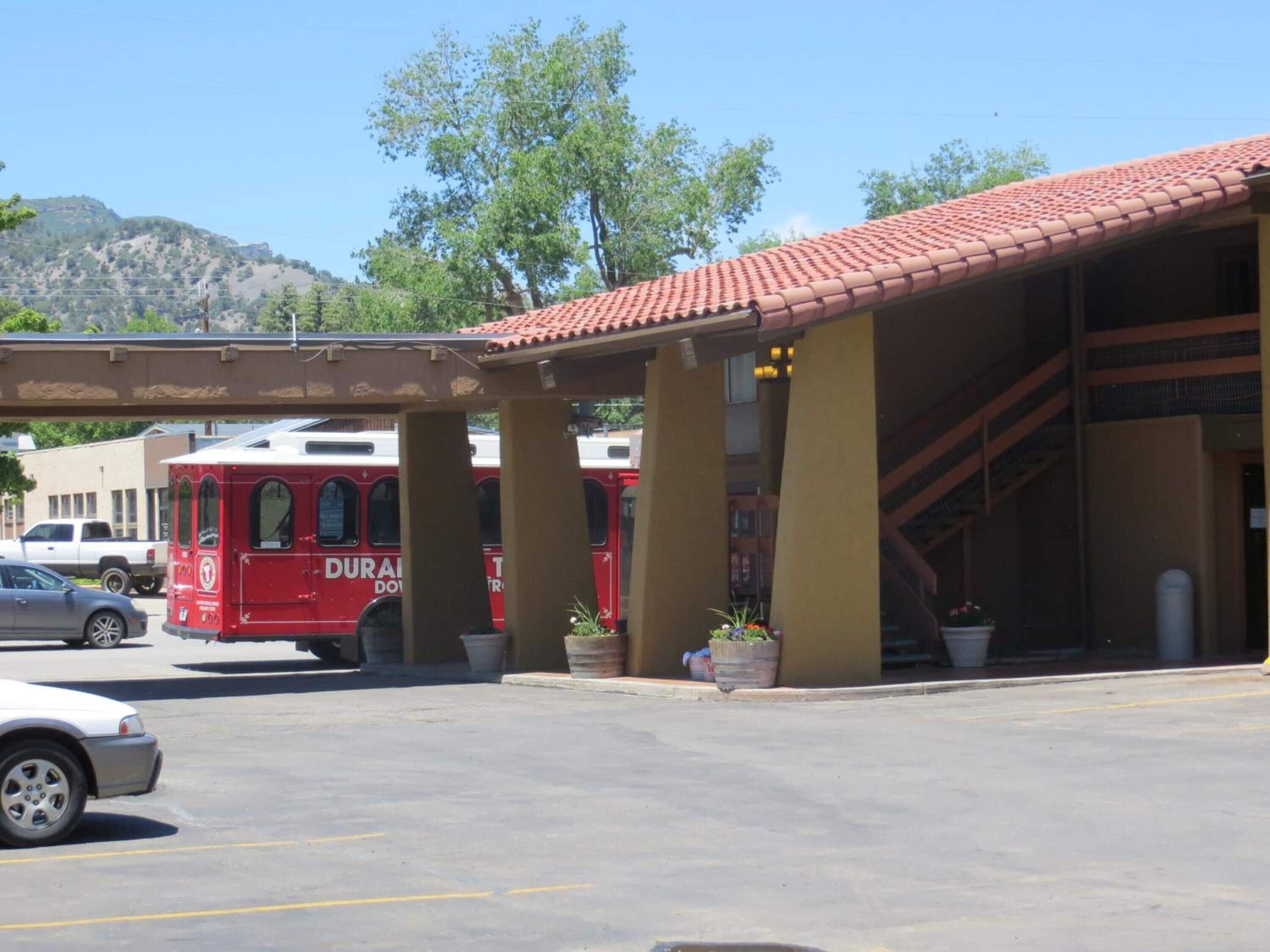 A parking area with a red bus labeled "DURAN" and a white car.