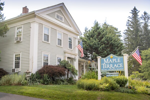 Una casa de dos pisos con un letrero que dice "Maple Terrace" y dos banderas estadounidenses.