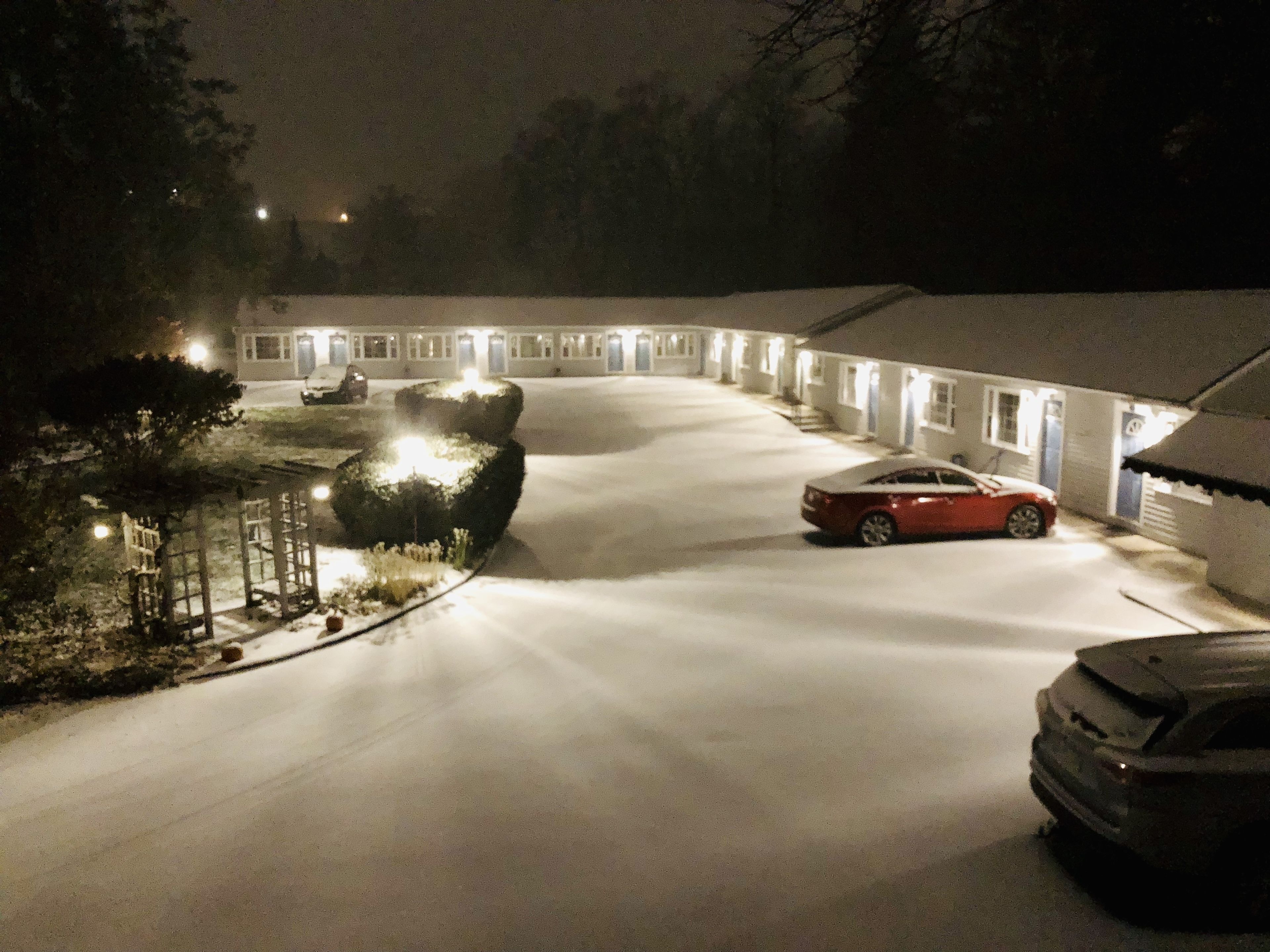 Una strada di accesso coperta di neve che conduce a una fila di edifici in stile motel con finestre illuminate.