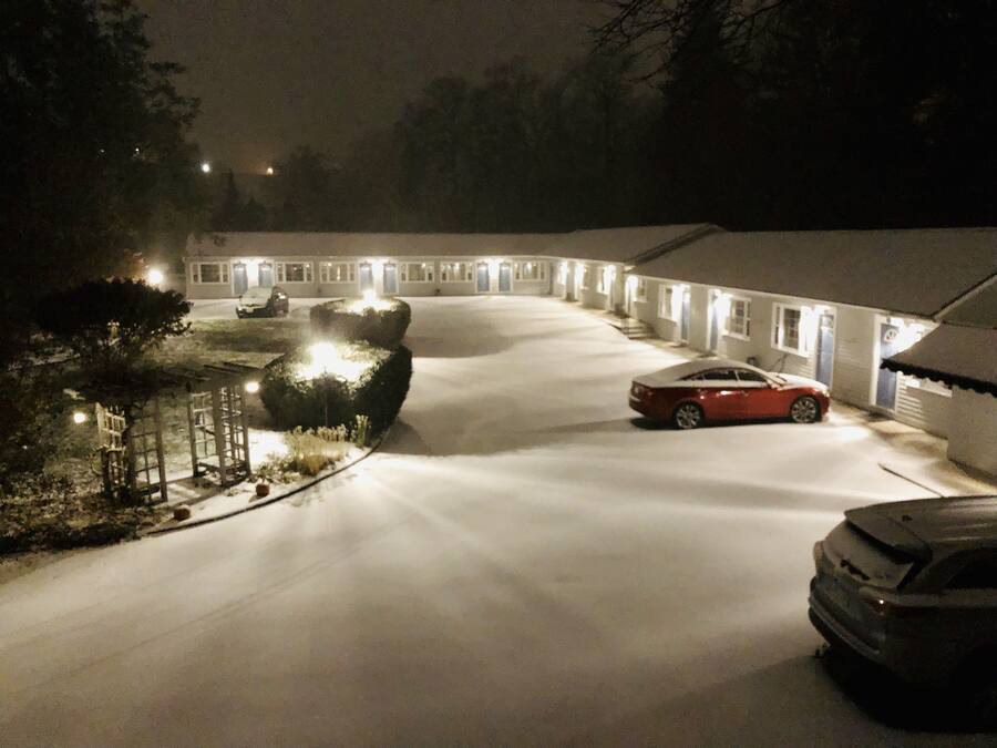 Una strada di accesso coperta di neve che conduce a una fila di edifici in stile motel con finestre illuminate.