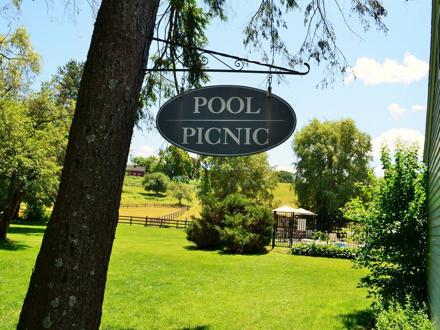 Un panneau indiquant une aire de pique-nique près d’une piscine, avec une pelouse clôturée et des arbres en arrière-plan.