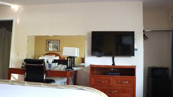 Ein Hotelzimmer mit Bett, Schreibtisch, Stuhl, Fernseher und Kommode.