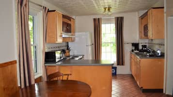 A compact kitchen with wooden cabinets, a refrigerator, a microwave, and a sink.