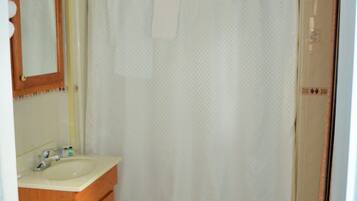 Baño con inodoro, lavamanos, espejo y cortina de ducha.