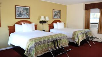 A hotel room with two beds, a wooden headboard, a red carpet, two wall-mounted lamps, and two paintings on the wall.