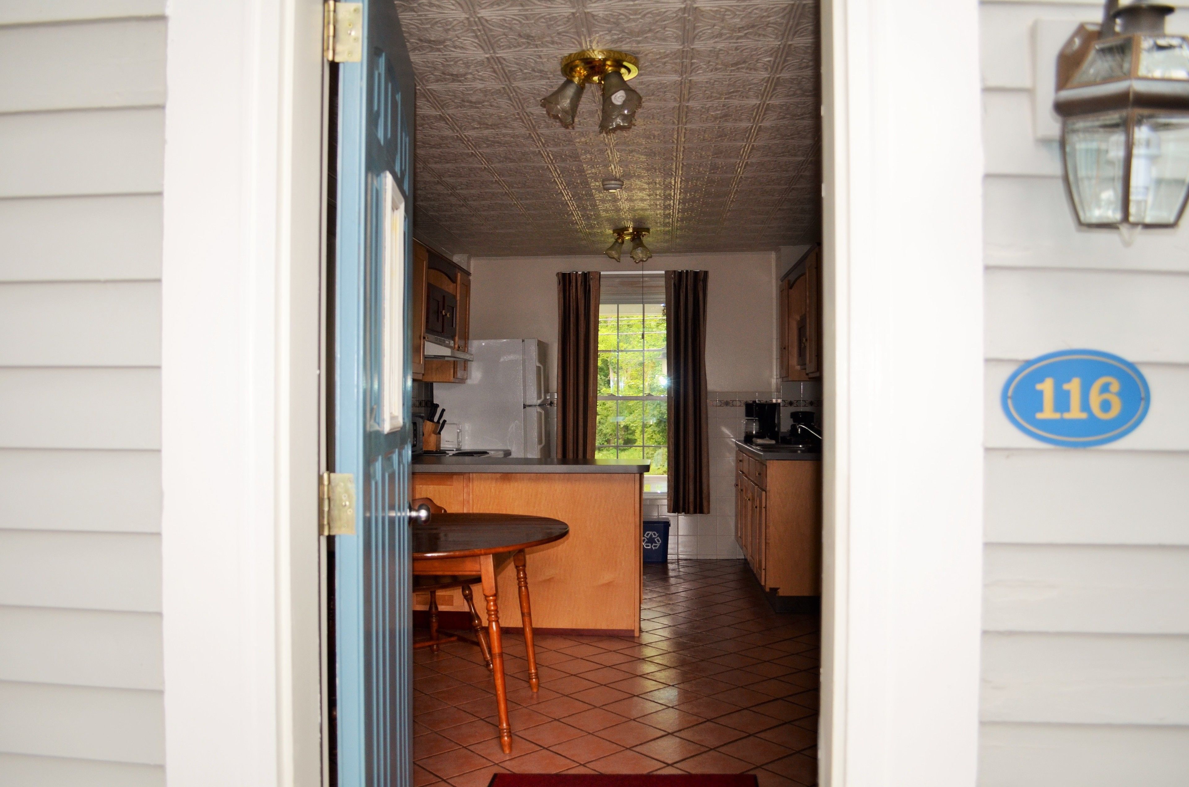 Una cocina con comedor, refrigerador y ventana con cortinas.