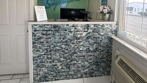 Un espace d’accueil agrémenté d’un mur végétal, d’une enseigne bleue portant l’inscription « Signature Inn » et d’un comptoir carrelé.