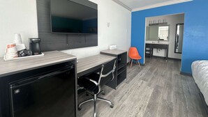 Une chambre d’hôtel équipée d’un bureau, d’une chaise, d’une machine à café et d’un téléviseur à écran plat fixé au mur.