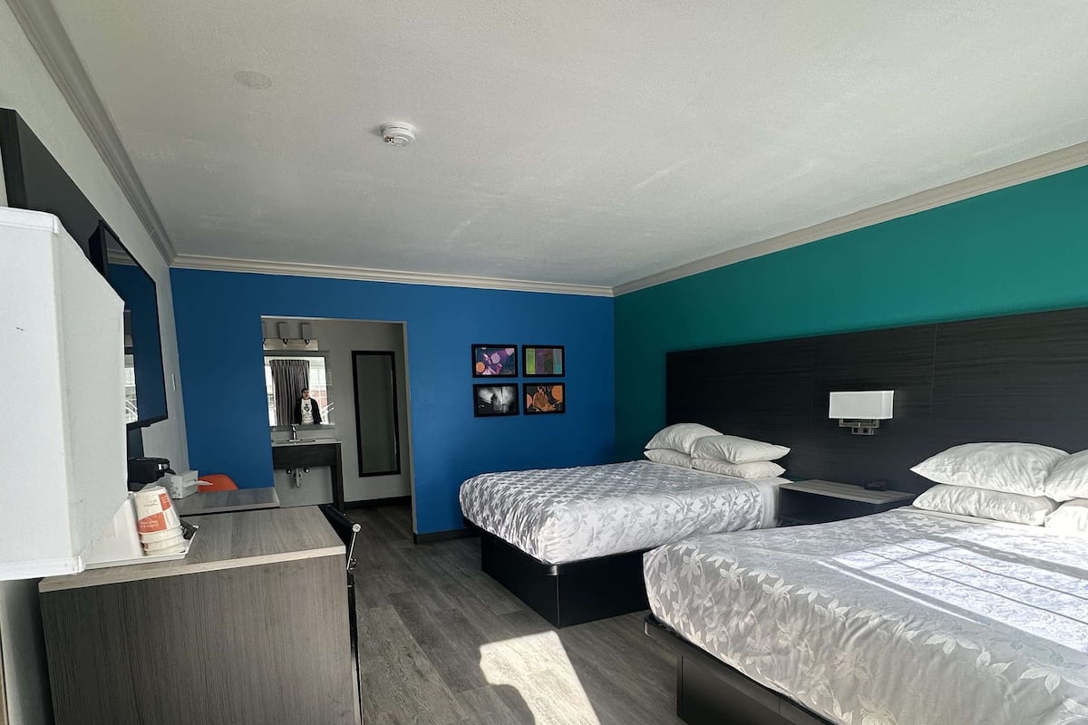 A hotel room with a large bed, a desk, and a small trash bin.