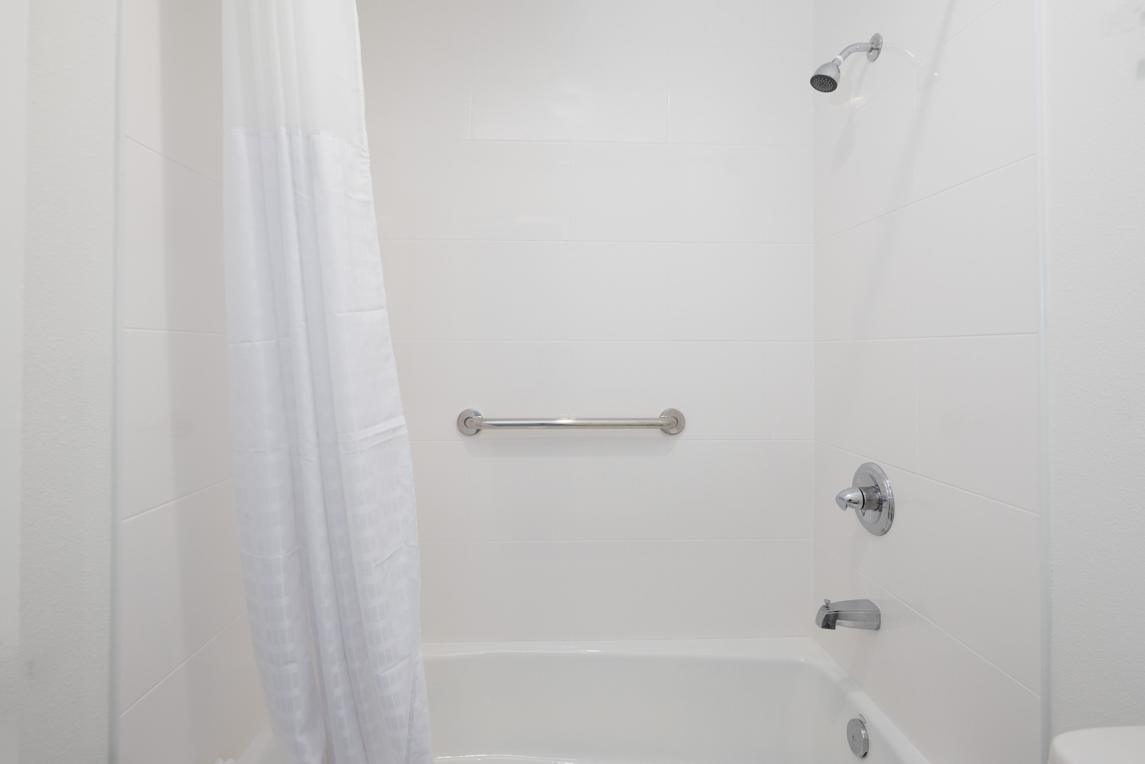 Ein Badezimmer mit einer Badewanne, einer Duschbrause und einer Handstange.