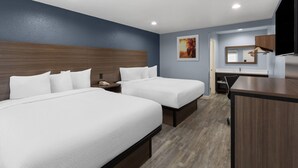 Een hotelkamer met twee bedden, een bureau, een spiegel en een televisie.