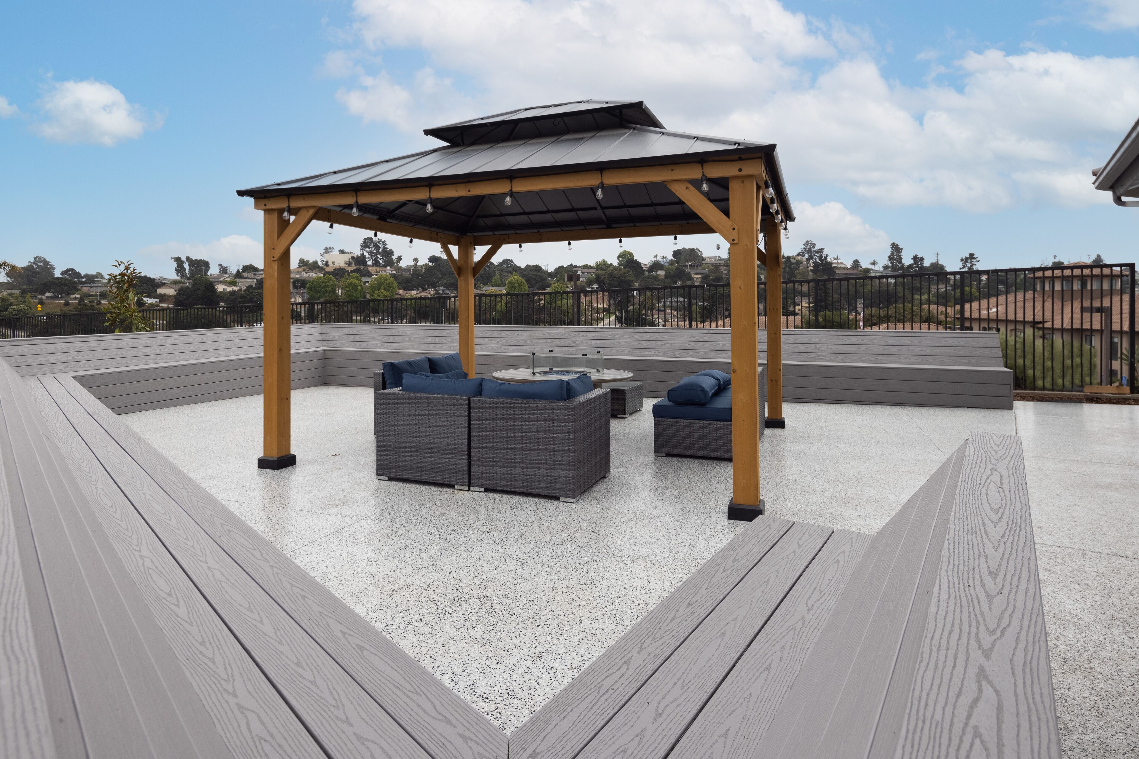 Una terraza en la azotea con pérgola, mobiliario exterior y vistas de la ciudad.