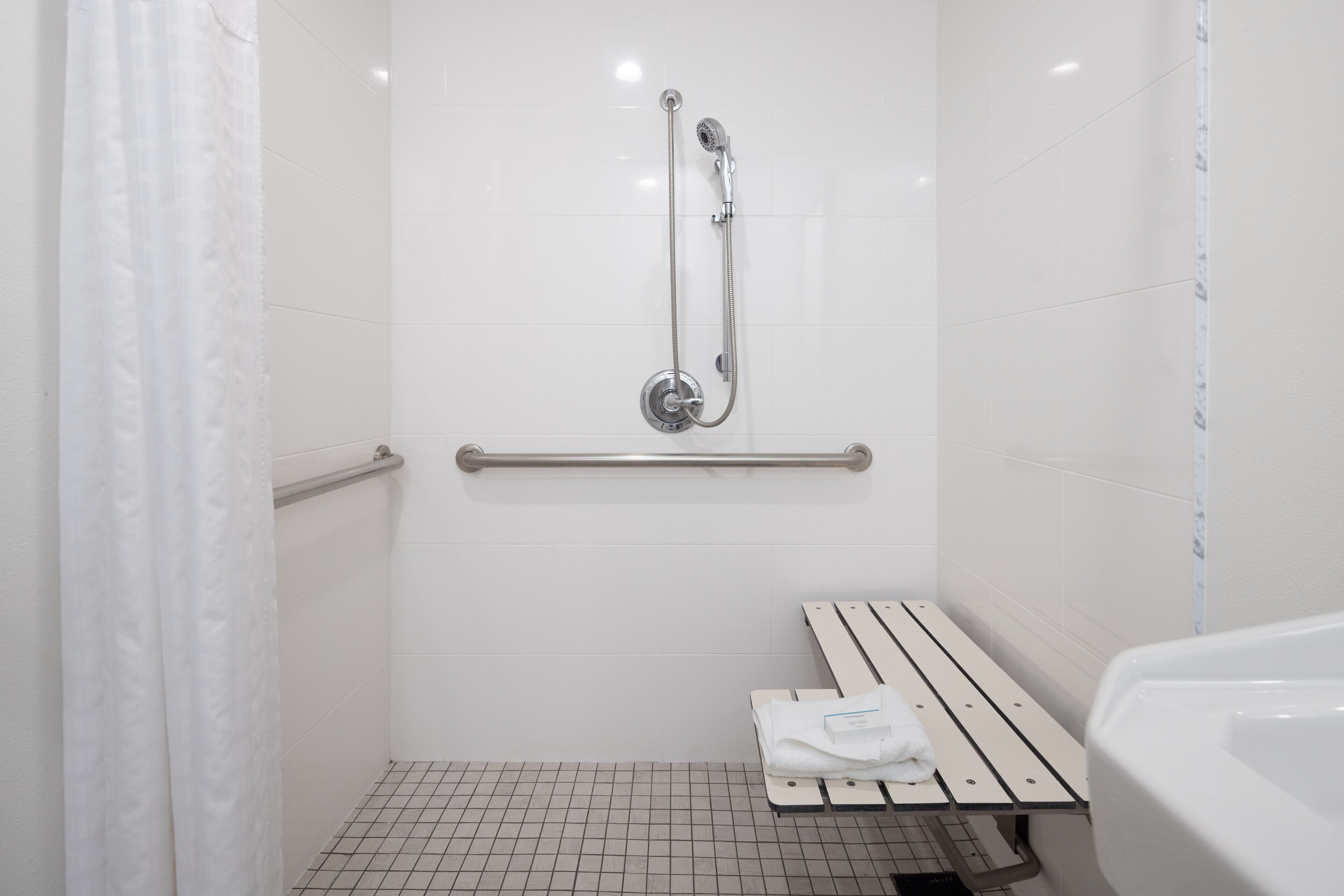 A bathroom with a shower, a bench, and a toilet.