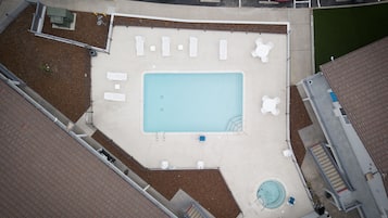 Luchtbeeld van een zwembad met ligbedden, een jacuzzi en een kleine tuin.