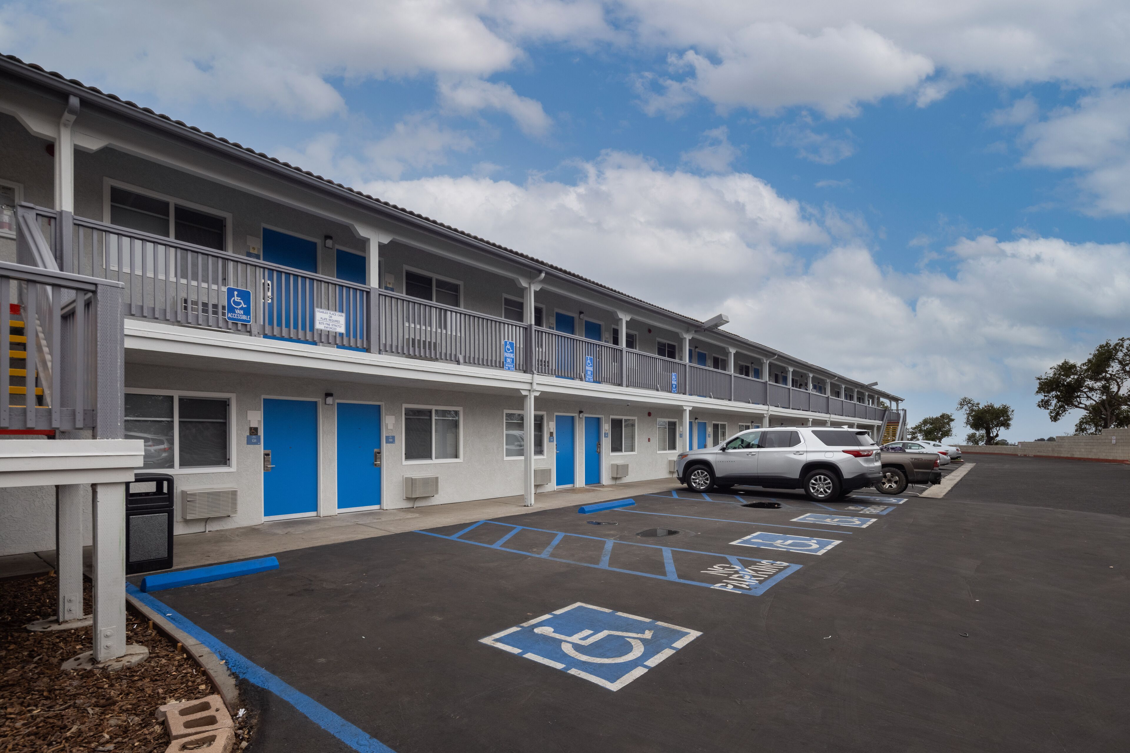 Een motel met verschillende kamers, een parkeerplaats en parkeerplaatsen voor gehandicapten.