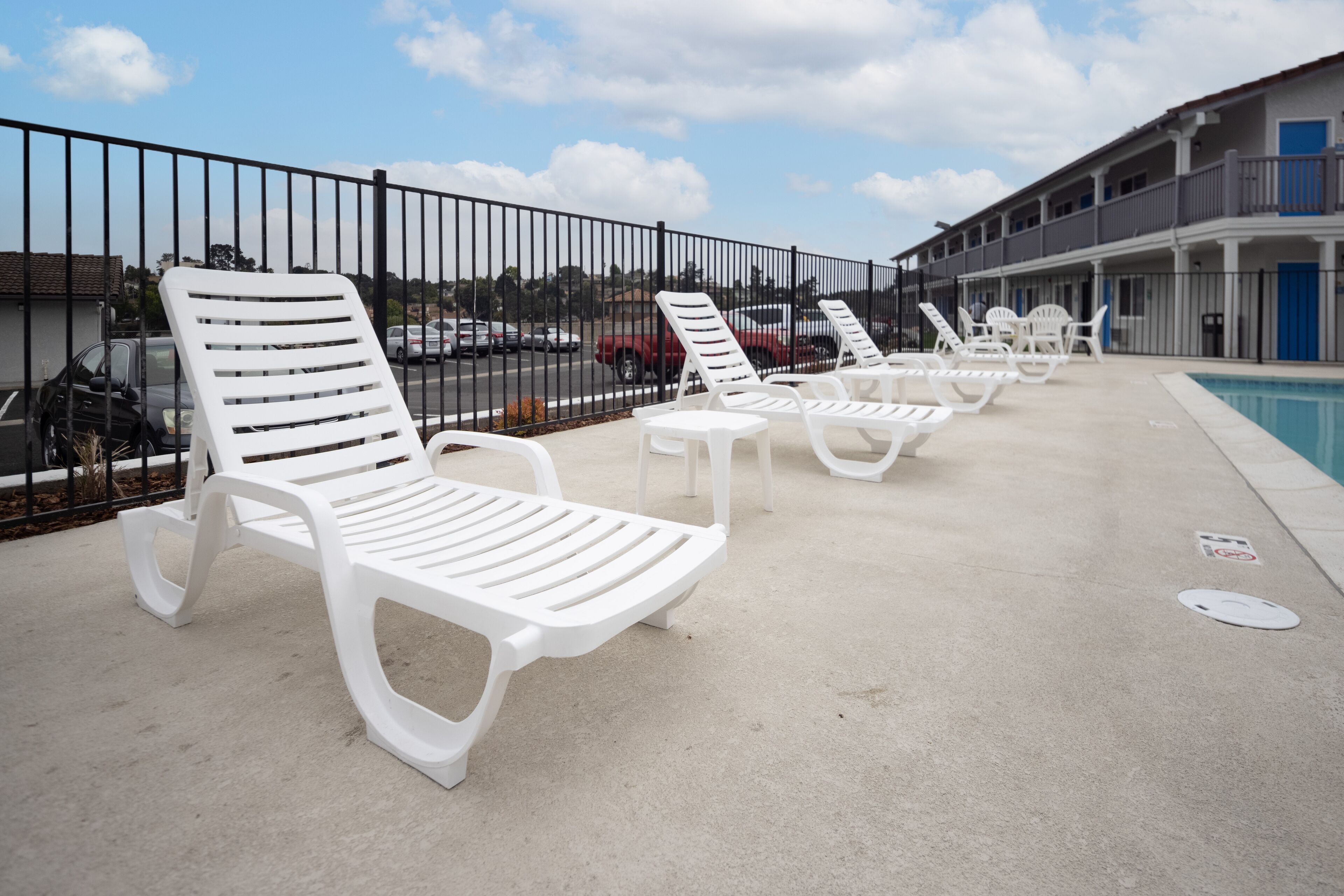 Un espace aménagé au bord de la piscine, avec des chaises longues blanches et une piscine.