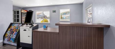 Ein Empfangsbereich mit Holztresen, einem Selbstbedienungs-Check-in-Terminal und Broschürenauslage.