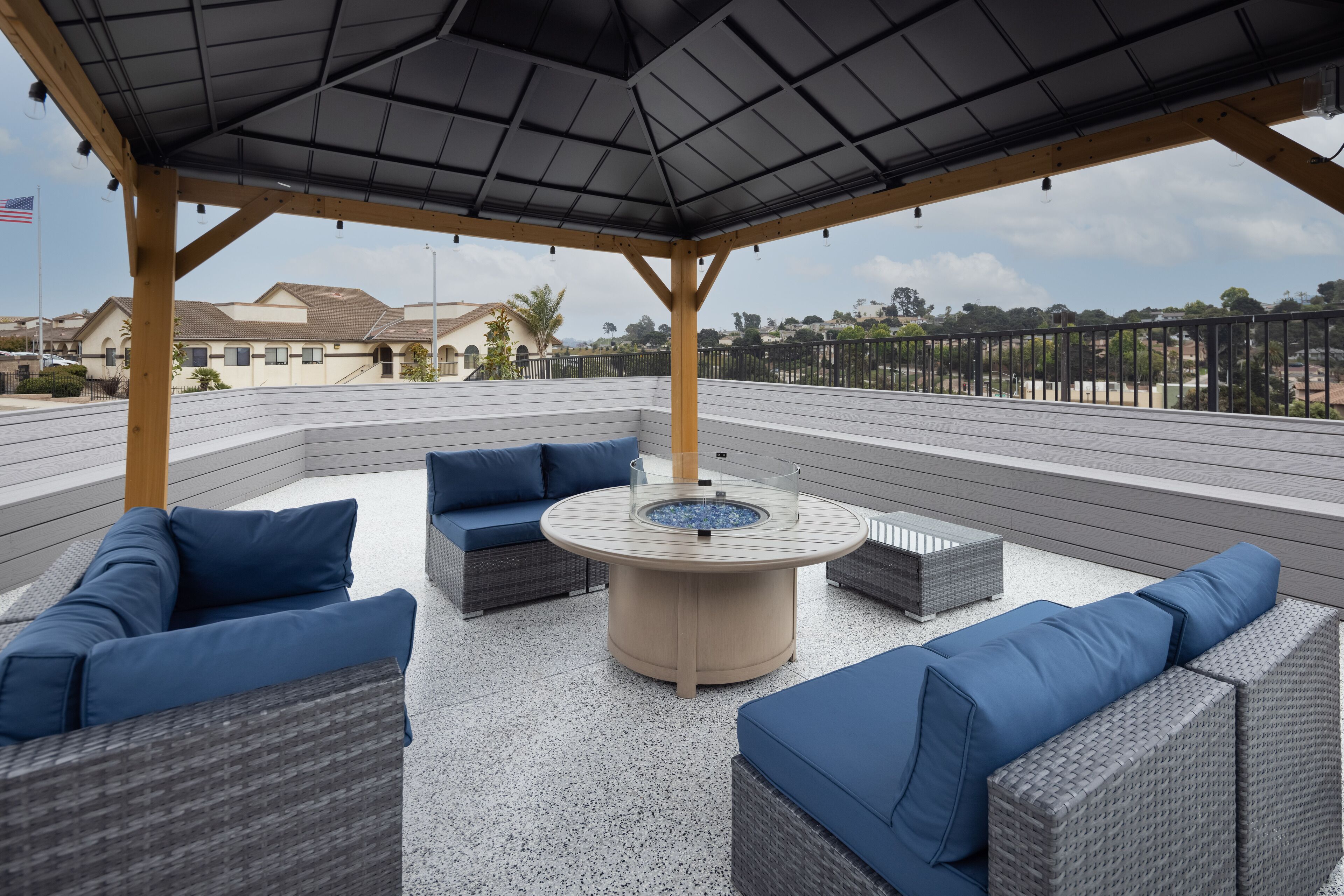 Un patio al aire libre con mobiliario de mimbre y un hogar central.