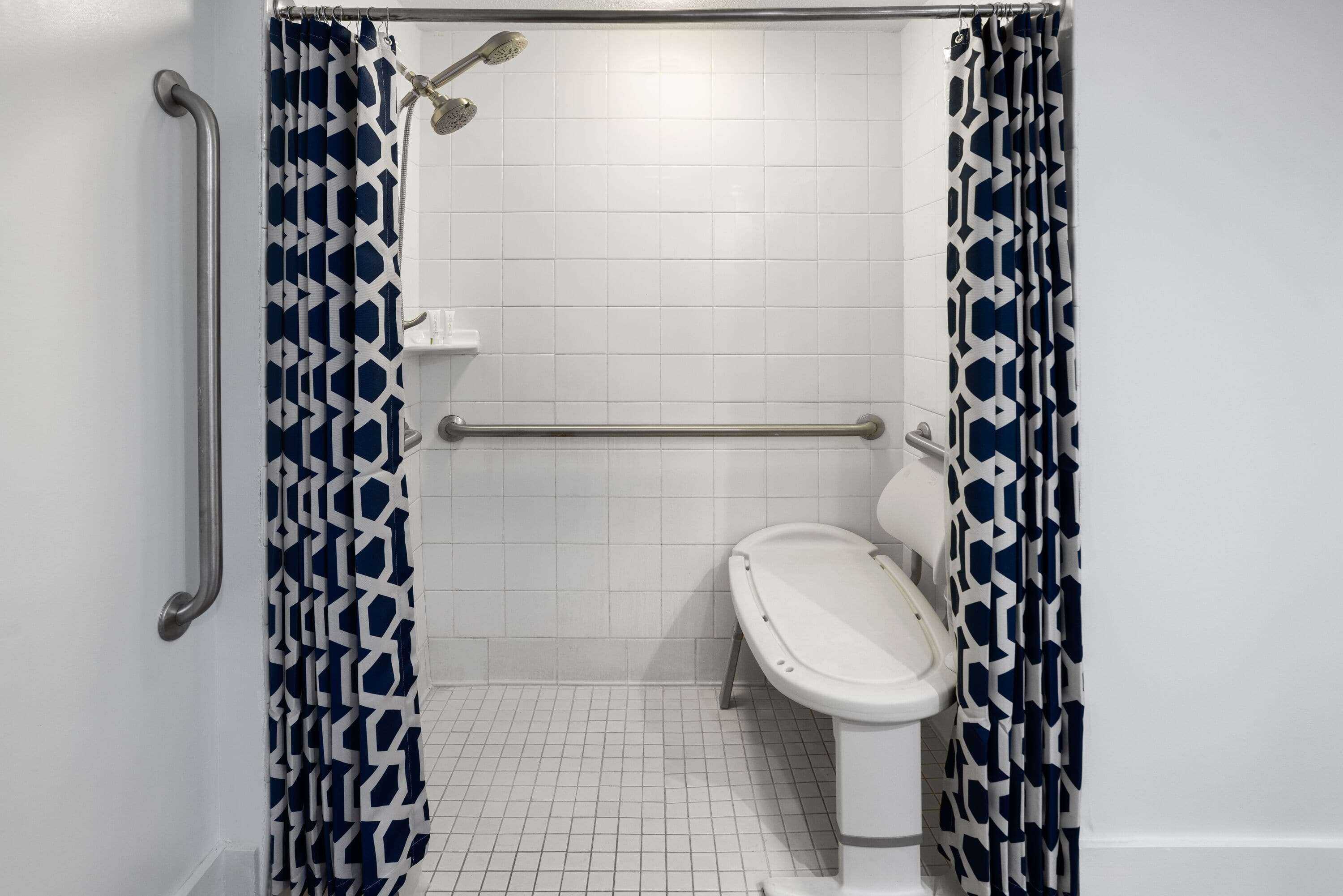 Une salle de bain équipée d’une douche, de toilettes et d’une barre d’appui.
