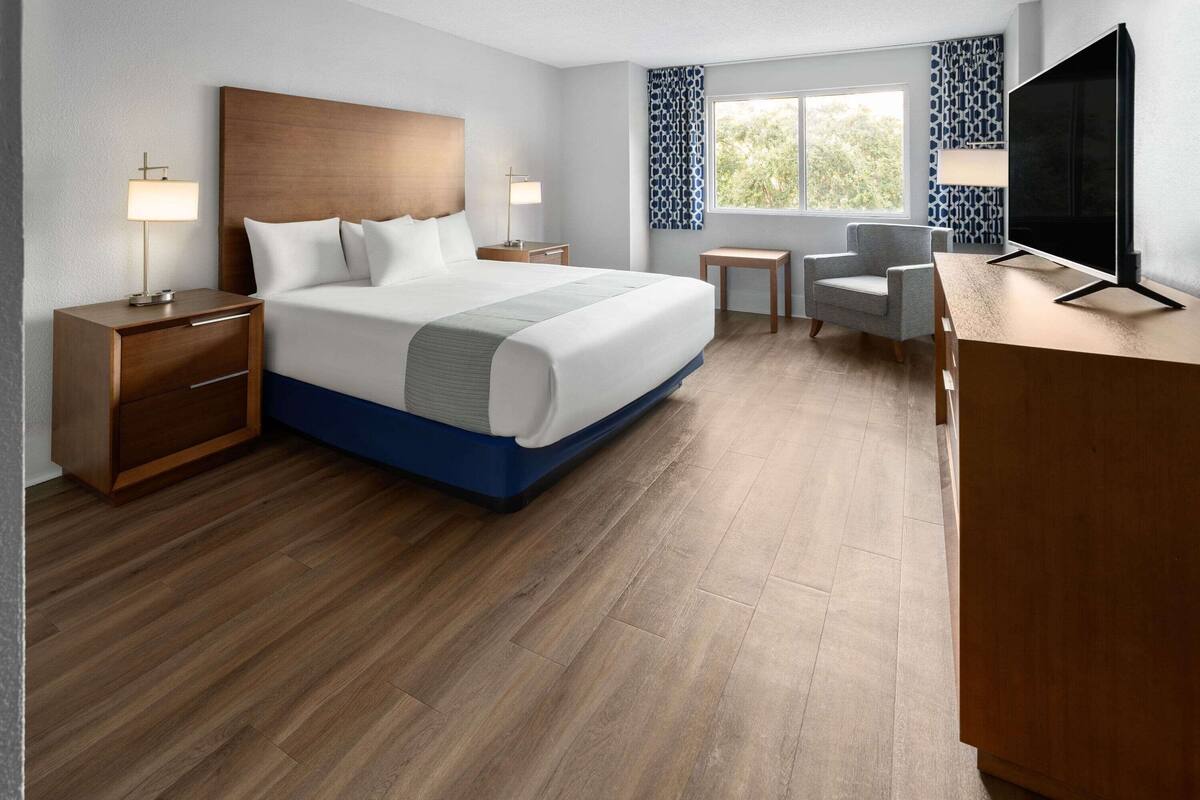 Une chambre d’hôtel moderne avec un grand lit, des tables de chevet, un bureau, une chaise et un téléviseur.