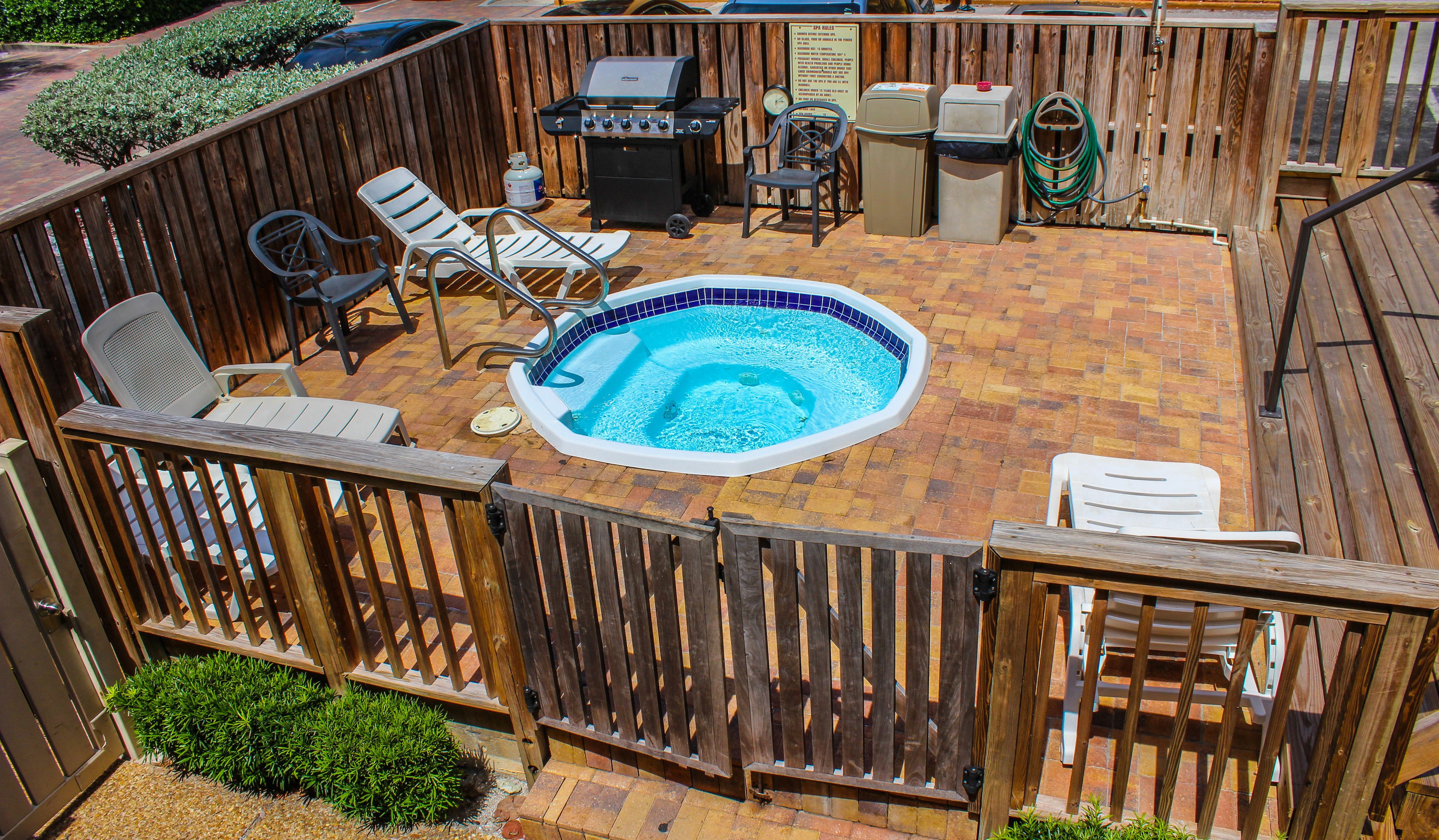 Un jardin avec un jacuzzi, un barbecue et un espace salon extérieur.