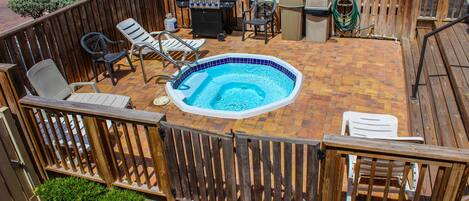 Un jardin avec un jacuzzi, un barbecue et un espace salon extérieur.