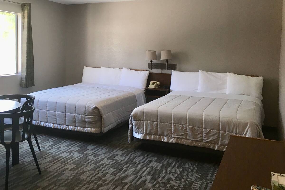 A hotel room with two beds, a desk, and a chair.