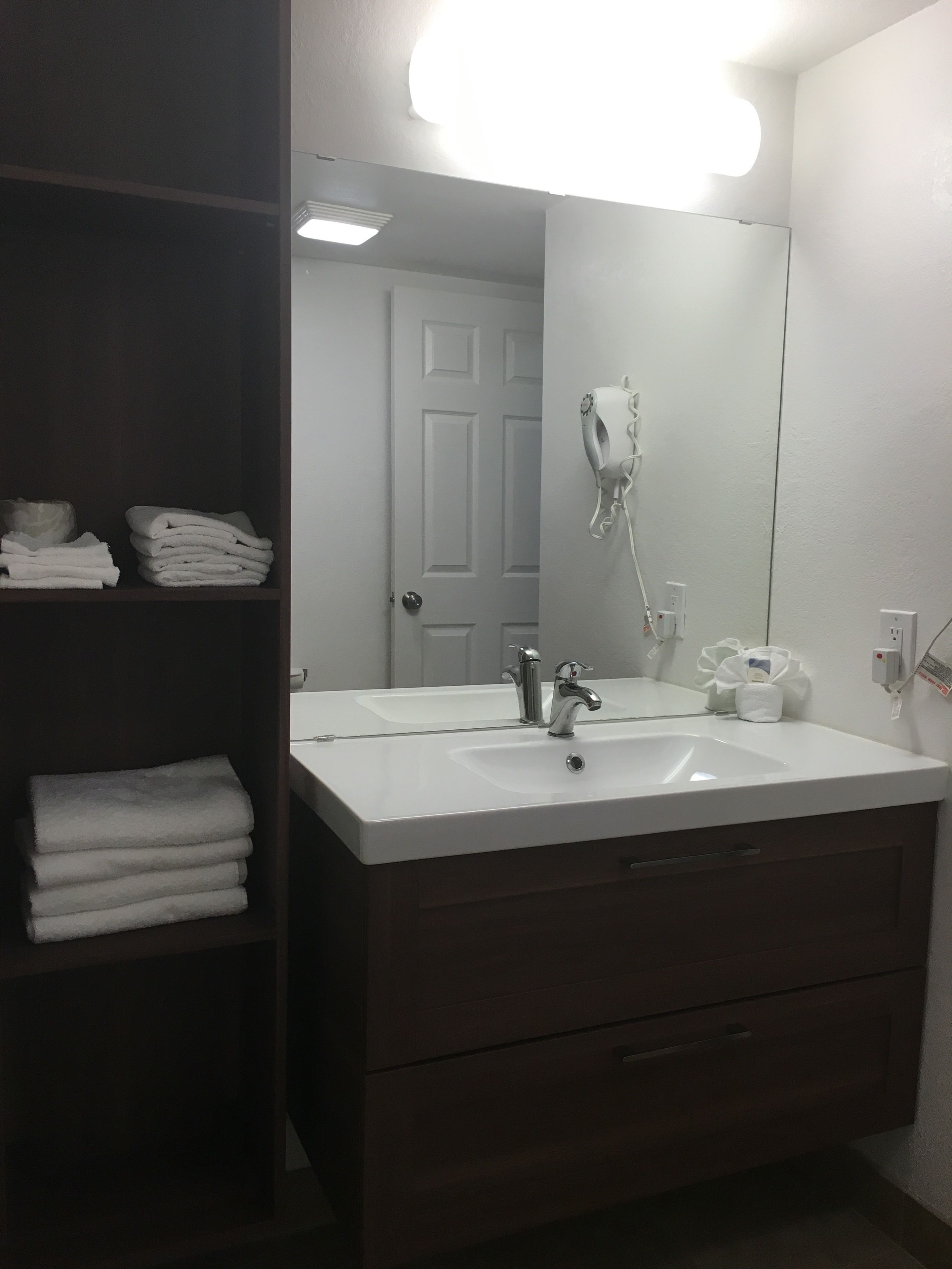 A bathroom with a white sink, a mirror, a towel rack, and a door.
