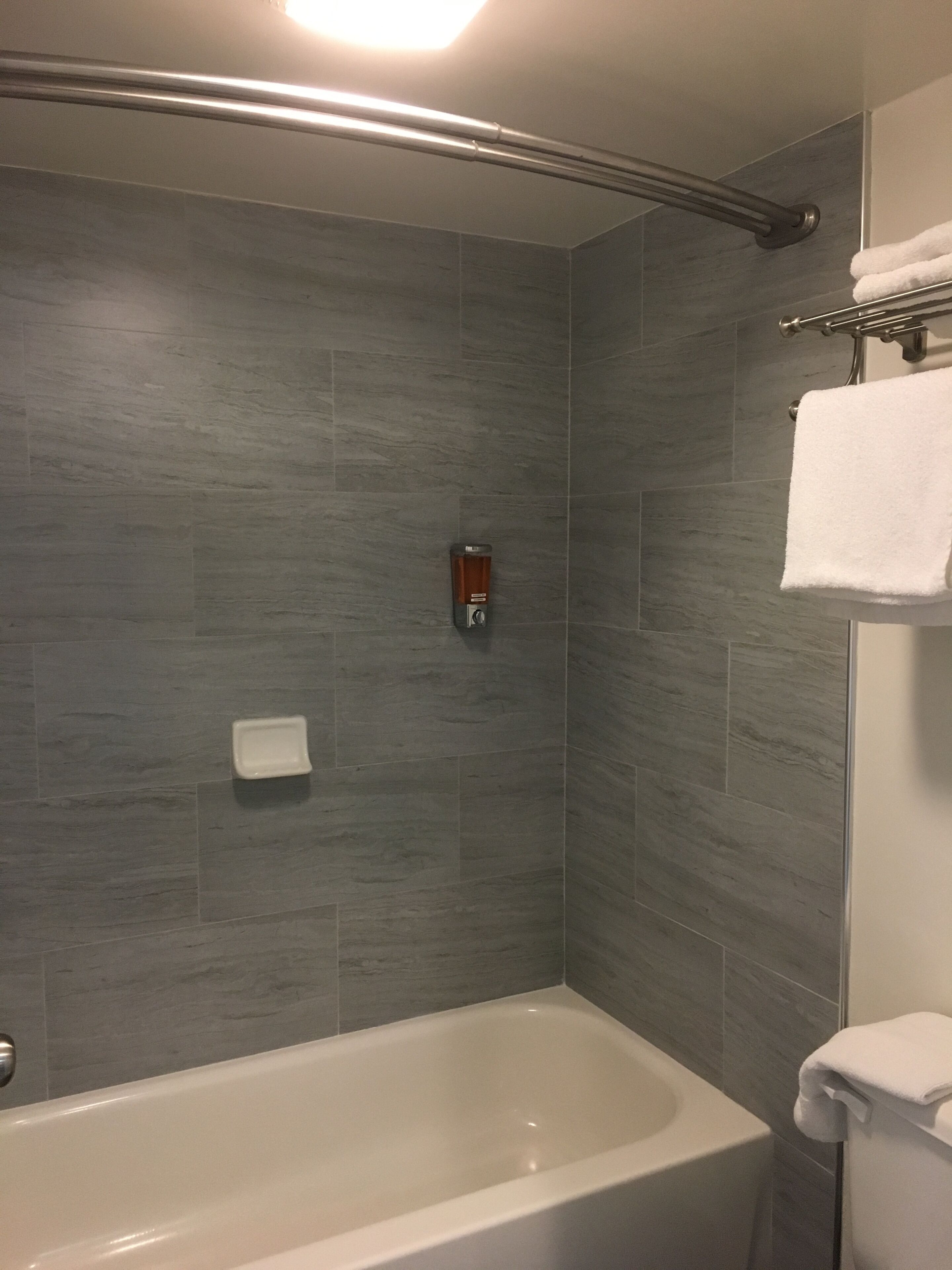 A modern bathroom with a bathtub, a shower area, and a towel rack.