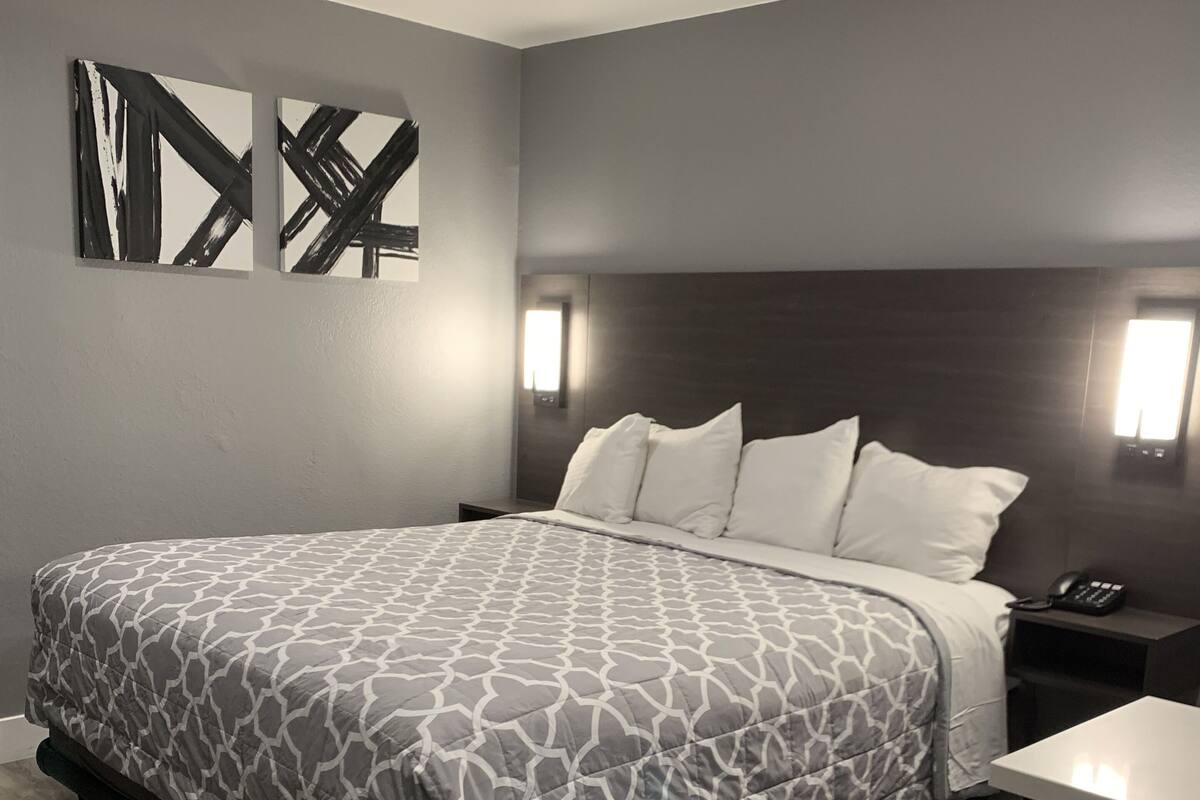 A modern hotel room with a large bed, a desk, and a chair.