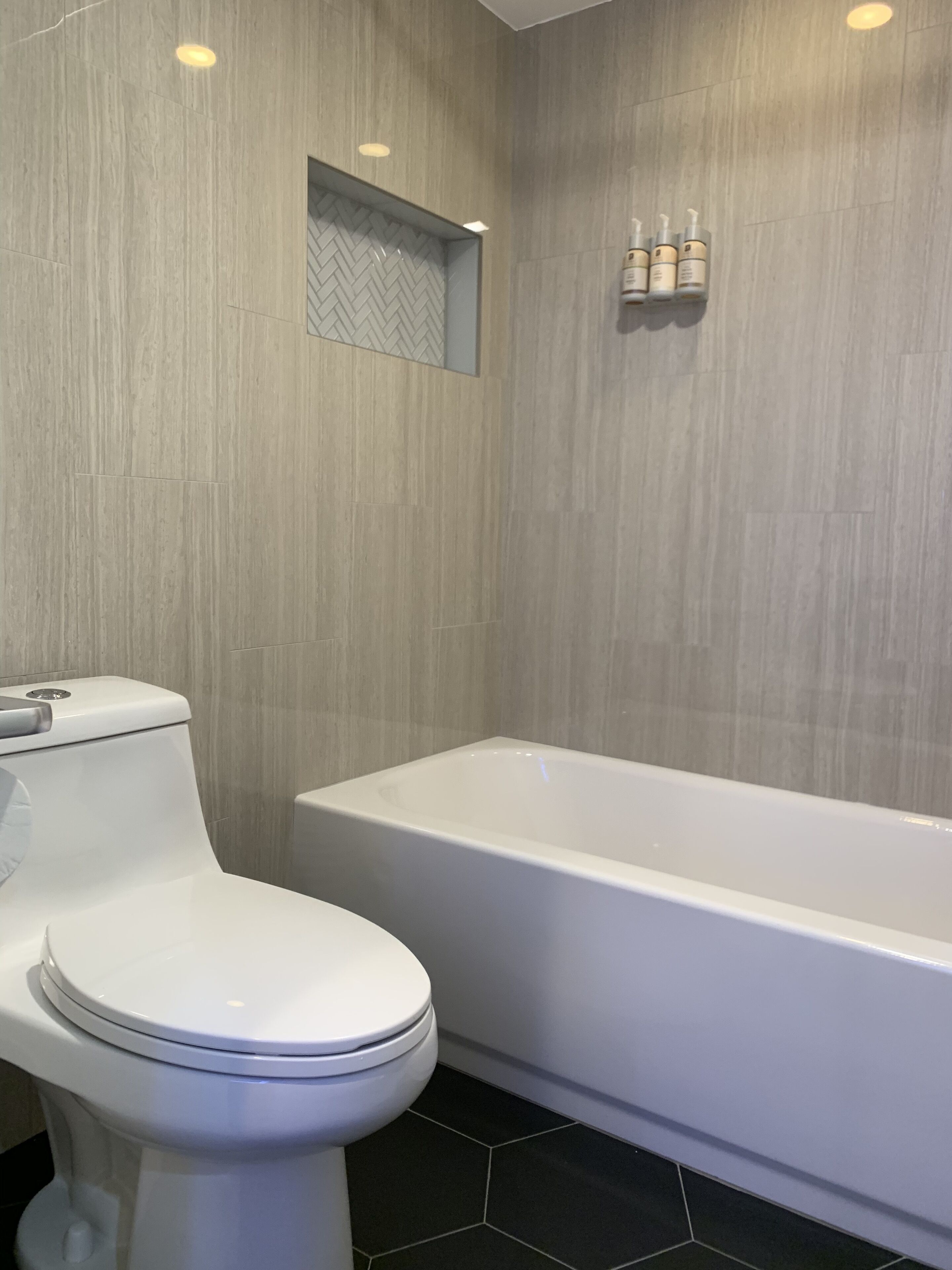 A modern bathroom with a toilet, bathtub, and a shower area.