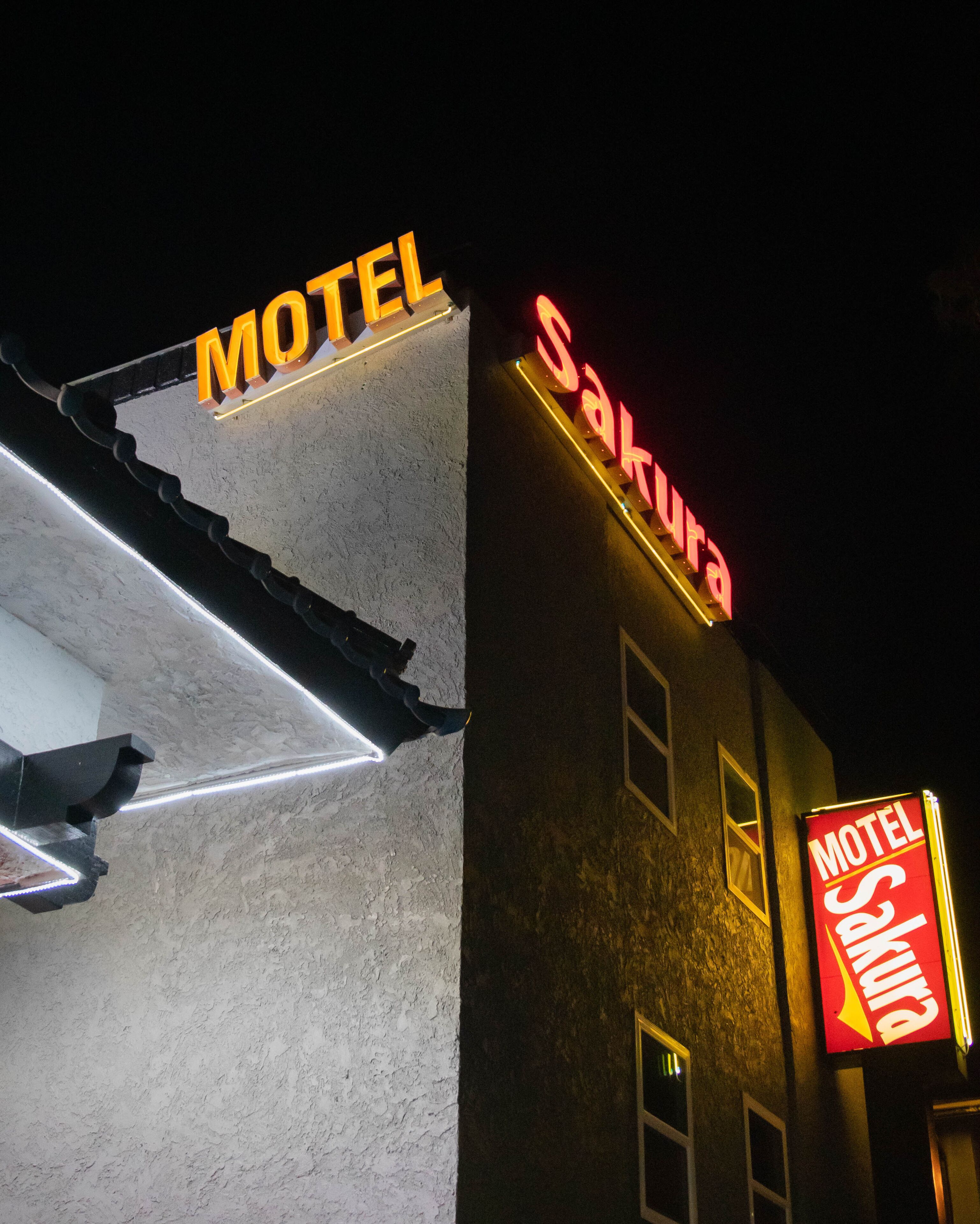 Un edificio con un letrero que dice "Motel Sakura" y otro letrero arriba que dice "Motel".