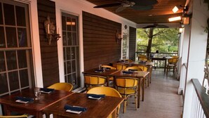 A covered outdoor dining area with wooden tables and yellow chairs. - The Red Lion Inn Resort 1704 (Cohasset)