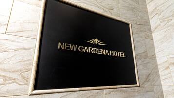 Un letrero negro con letras doradas del Hotel New Gardenah.