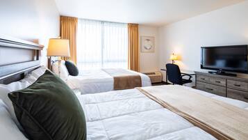 A hotel room with two beds, a television, a desk, and a chair.