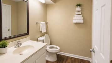 A bathroom with a sink, mirror, toilet, and a towel rack with towels.