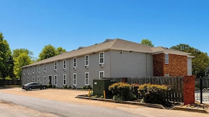 A multi-story building with a parking lot and a gated entrance. - Plantation Oaks Suites & Inn Millington (Millington)