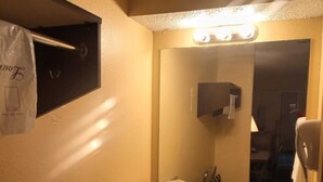 Un baño con lavamanos, espejo y perchero para toallas.